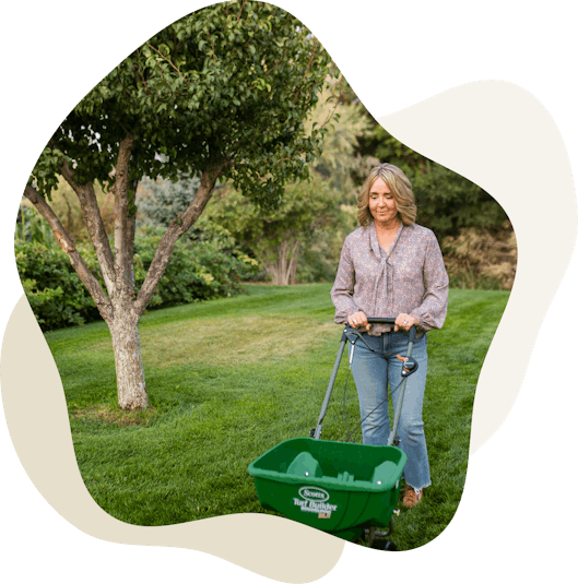 Woman pushing fertilizer spreader