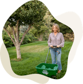 Woman pushing fertilizer spreader